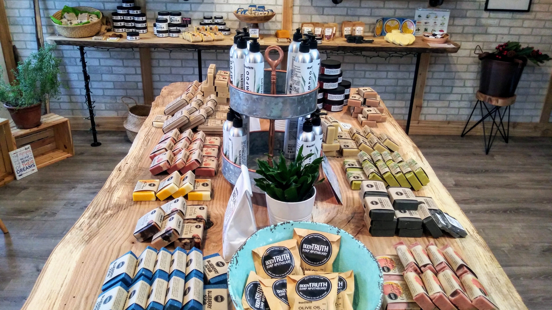 The Bodytruth brick and mortar store — white brick, wooden shelves, soaps, plants, and community